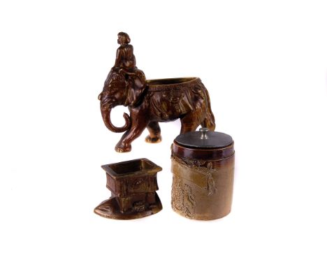 A stoneware tobacco jar,  with die case decoration, without cover, 12cm high, together with another modelled as an elephant (