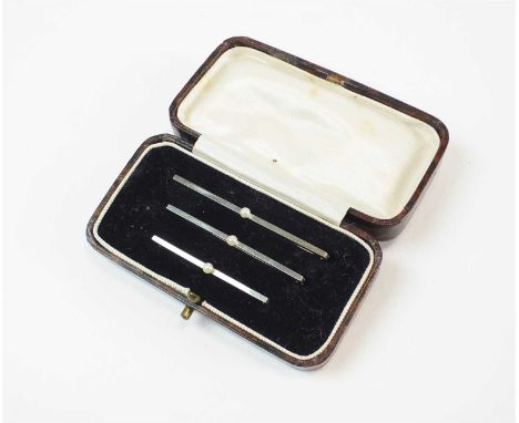 A cased set of three graduated pearl brooch/pins, each deigned as a single bar set with central seed pearl, the reverse of ea