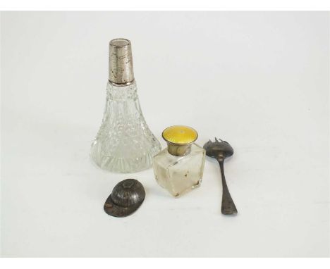 A silver caddy spoon in the form of a jockeys cap, together with a silver and yellow guilloche enamel topped glass bottle, a 