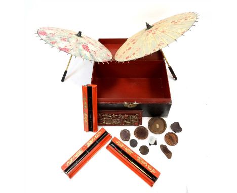 A Chinese lacquered trunk containing a collection of Chinese hardwood stands, two Chinese painted parasols and four Chinese c