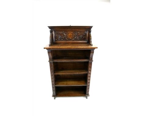 A small Victorian oak free-standing bookcase, the top backed with a raised panel decorated with shallow relief carved stylise