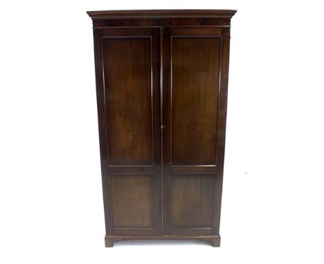 An early 20th century mahogany wardrobe, the hinged panelled doors below a flamed frieze and stepped cornice, opening to reve