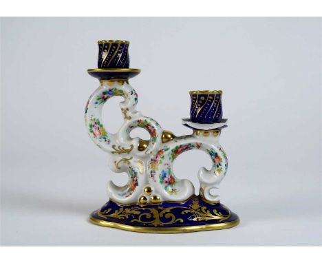A French porcelain double candlestick circa 1956, the two nozzles support on rococo scrollwork (losses to one nozzle and scon