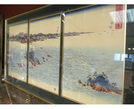 A 19th Century Japanese woodcut print in three sections depicting turbulent sea around rocky outcrops and islands.  Framed an