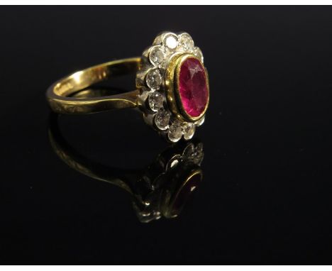 An 18ct gold ruby and diamond ring the centre ruby framed by twelve round cut diamonds