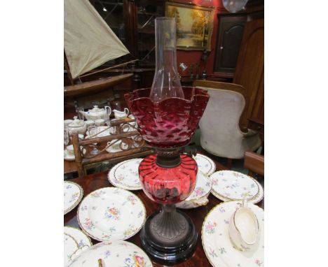 A late 19th Century Falk Stadelmann oil lamp with dark cranberry dimple shade above melon fluted reservoir embossed metal foo