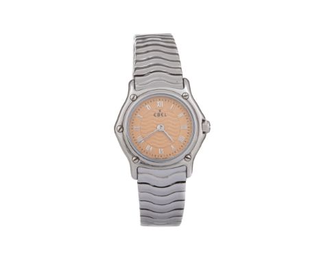 the round orange dial with Roman hour markers, outer seconds track in black, 24mm case, on a stainless steel bracelet with co