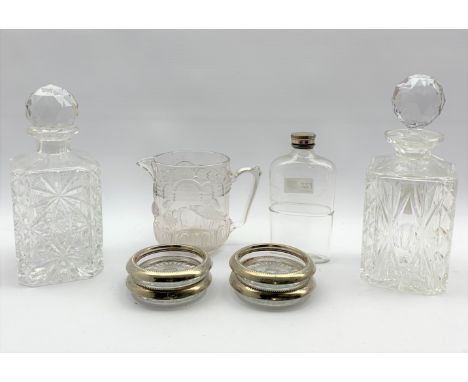 Two square cut glass spirit decanters, set of four Italian glass coasters with plated rims, moulded glass jug with swan and f