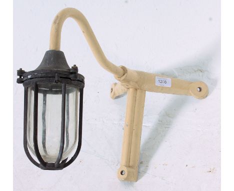 A vintage 1950's industrial dairy lamp complete with glass drop shade and cage with painted metal bracket