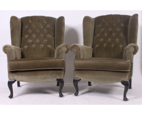 A pair of antique style wingback armchairs raised on cabriole legs with button backed green velour upholstery. All raised on 