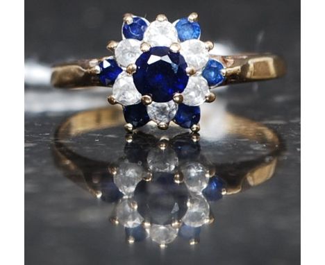 A 9ct gold, diamond and sapphire flower head ring. The central blue stone 20pnts with 6 surround 1pnt diamonds. Ring size O/P