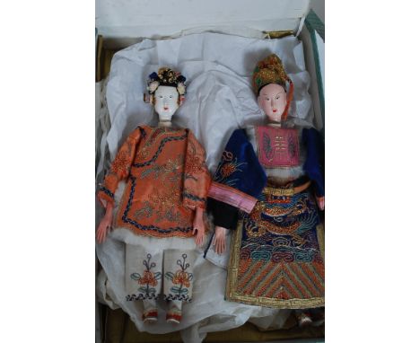 A pair of early 20th century Chinese male and female dolls dressed in full court regalia being boxed. Each with ceramic heads