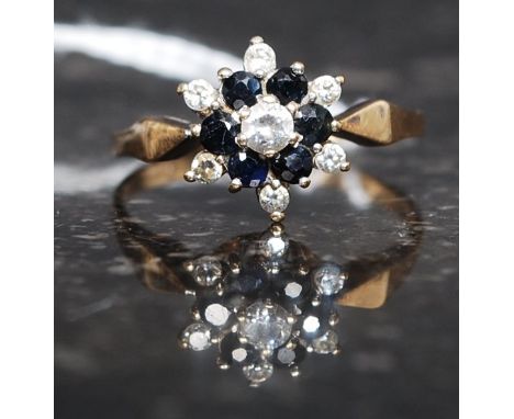 A 9ct gold, diamond and sapphire flower head ring. The central stone approx 2pnts with 6 surround 1ct diamonds. Ring size Q 1