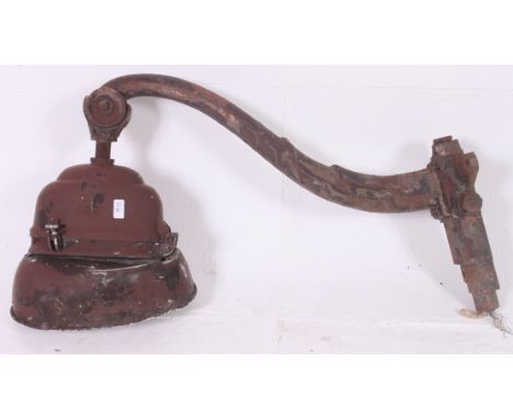 A large vintage industrial work light on large cast iron shaped bracket with unusual shaped light. 
