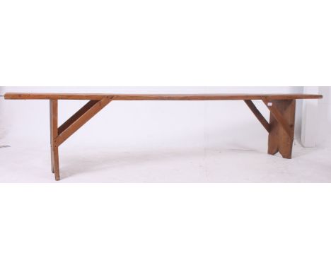 A 19th century French provincial pine refectory pig bench having a planked top with angled supports to the underside. Near Ma