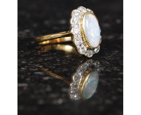 An 18ct gold, diamond and opal ring, the oval cabochon cut stone with diamond surround, approx 6g