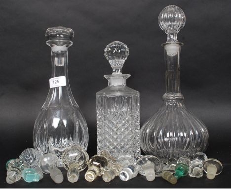 Three vintage glass decanters along with a selection of decanter and bottle stoppers