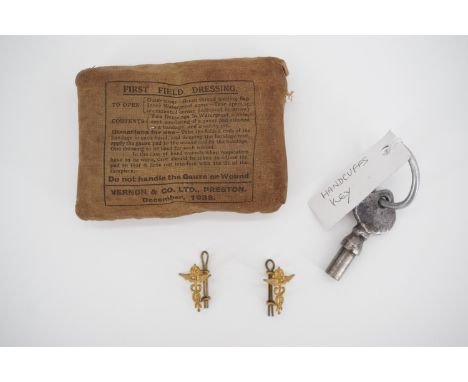 A Second World War army first field dressing, two RAF badges and a broad-arrow-marked handcuff key
