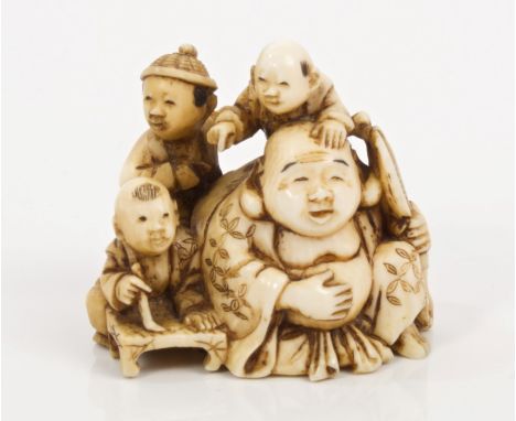 Late 19th century Japanese carved ivory netsuke of Buddha holding a fan, with three children - signed, 4cm wide   CONDITION R