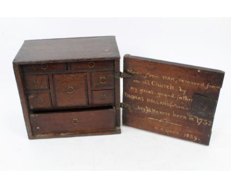 18th century oak cupboard with geometric panelled door, enclosing fitted interior of drawers, the reverse of the door inscrib