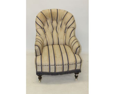 Victorian upholstered deep armchair, button upholstered in striped fabric, on turned legs and ceramic castors 