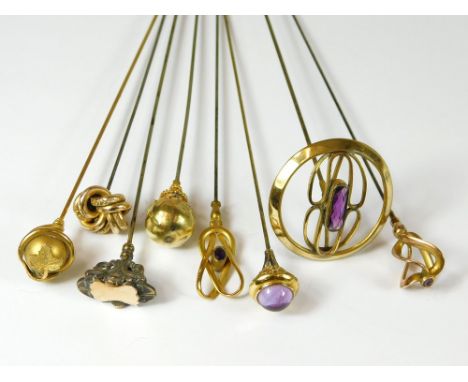 GILT METAL HAT PINS. Eight gilt metal or gold plated hat pins, including four set with amethyst coloured stones. Longest 26cm