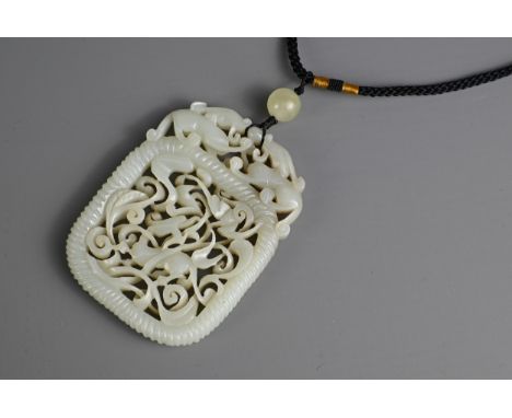 A CHINESE PALE CELADON JADE PENDANT. Carved and pierced featuring a deer and bat amidst leafy scrolls within a rope twist bor