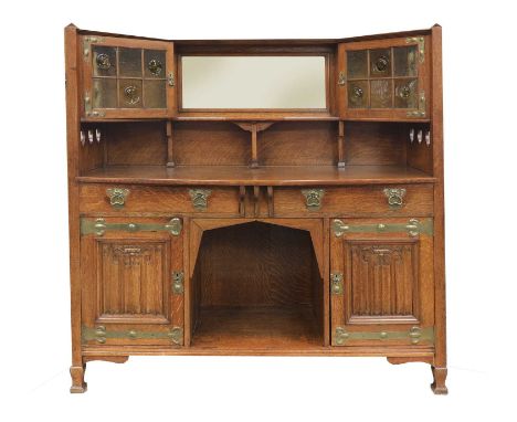 An Arts and Crafts oak sideboard,by Shapland &amp; Petter, Barnstaple, centred with a bevelled mirror plate and a shelf, flan