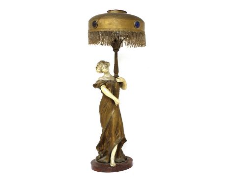 An Art Nouveau patinated spelter and bisque table lamp, modelled as maiden with bisque arms, head and shoulders holding a bal