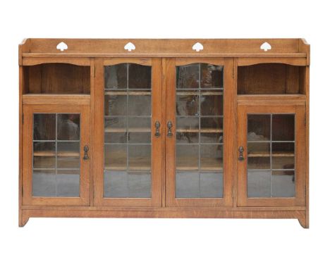 An Arts and Crafts glazed oak bookcase, by Liberty and Co., with a fret-cut three-quarter gallery, centred with leaded glass 