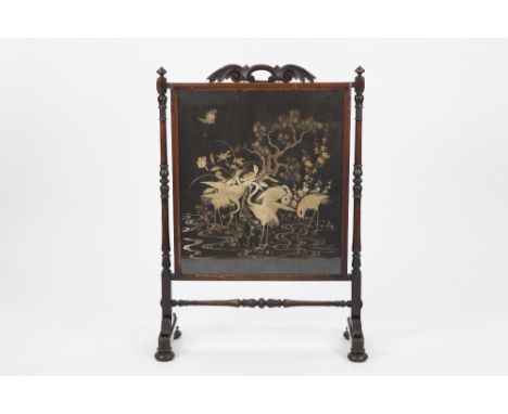 NINETEENTH CENTURY CARVED ROSEWOOD FIRESCREEN, the oblong panel hand worked in raised threads with a detailed scene of storks