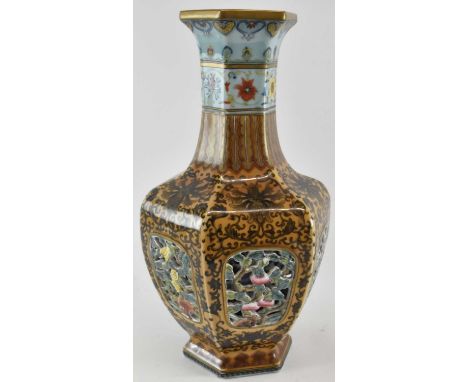 A modern Chinese double walled reticulated hexagonal baluster form vase, with pierced floral decoration enclosing blue and wh
