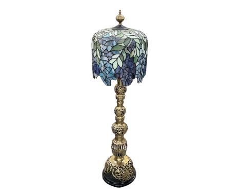 An early 20th century brass tabletop reading lamp, with coloured leaded glass shade, raised on carved hardwood base, height 1