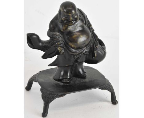 A late 19th century Chinese bronze figure of Hotei, standing upon a low table, height 11.5cm.