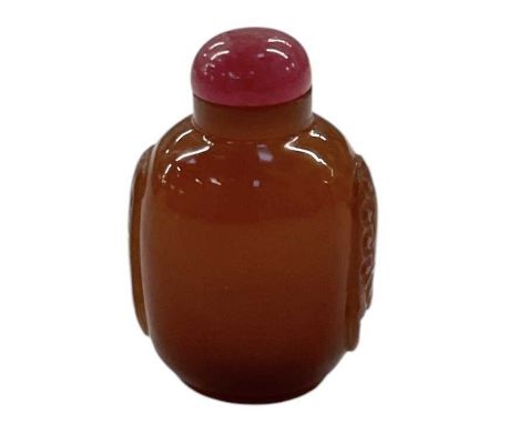 A Chinese carved amber coloured glass snuff bottle, with pink carved hardstone lid and bone snuff spoon, height 7cm.