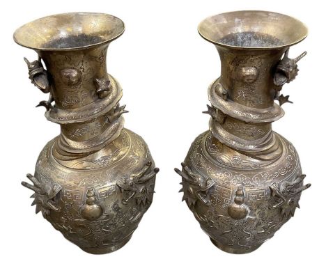 A pair of early 20th century Chinese brass baluster form vases, decorated with a dragon and further dragon scrolling around t
