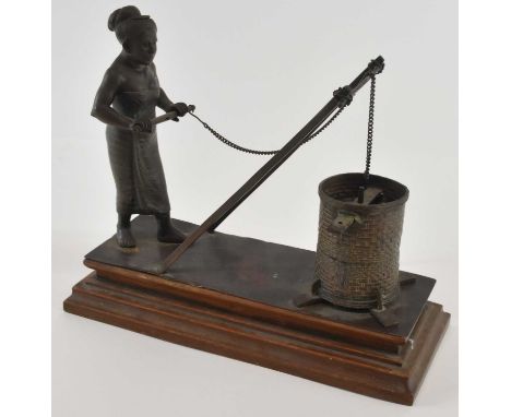A Cambodian Khmer bronze of a well worker, raised on stepped wooden plinth base, height 18.5cm, width 26cm.