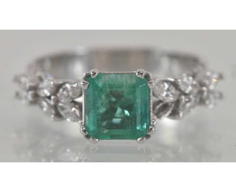 An 18ct white gold emerald and diamond set ring, the central square cut emerald approx 1.15ct, flanked by two sets of six mar