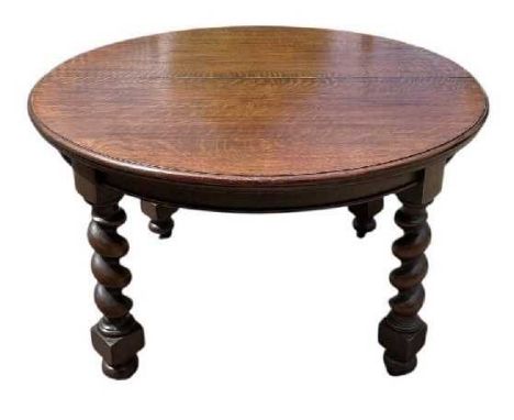 An early 20th century oak circular extending dining table, with three additional leaves, raised on barley twist supports, dia