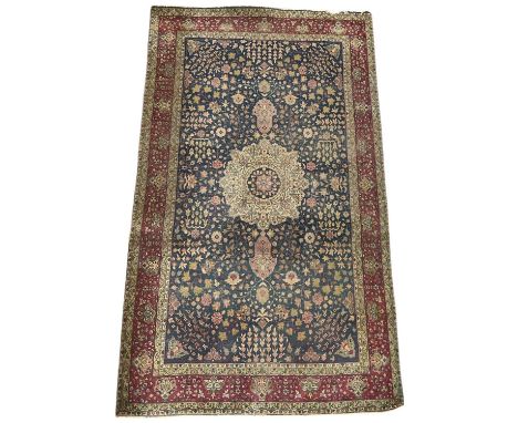 A Persian hand woven blue ground 'Tabriz' type carpet, decorated with foliage and medallions, with red and cream border, 180 
