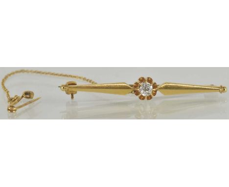 A gold bar brooch with central raised claw set diamond, unmarked, length 4.5cm, with gold safety chain, combined approx 4.7g.