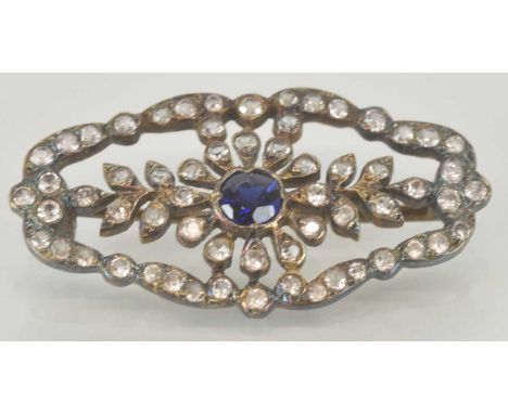 An Edwardian open diamond and sapphire set brooch, with central cut bezel set sapphire, the unmarked metal frame set with tin