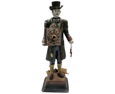 An early 20th century painted cast iron clock modelled as a gentleman holding a clock movement aloft, dangling the weights an