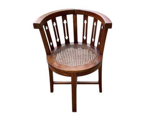A reproduction Arts and Crafts style walnut bergère seated barrel type chair, with carved slat backs, width 59cm.