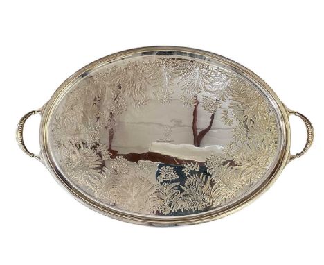A large early 20th century oval twin handled silver plated tray, with embossed floral decoration and engraved family crest, 7