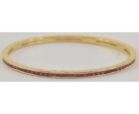 A yellow metal ruby set eternity bangle, diameter 7cm, approx 10g.