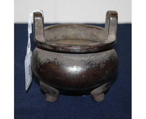 A reproduction Chinese bronzed alloy censor, of squat circular form with twin handles and on tripod supports, with pseudo sea