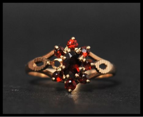 A hallmarked 9ct gold and garnet cluster ring with diamond cut pierced shoulders. Hallmarked Birmingham. Size R. Weight 2g. (