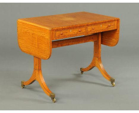 A Regency style satinwood veneered sofa table, each flap with rounded corners, the frieze fitted with two drawers and two opp