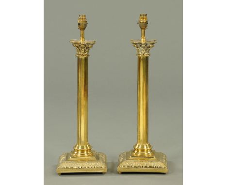 A pair of Victorian brass table lamp bases, converted to electricity and each raised on a square stepped base.  Height exclud